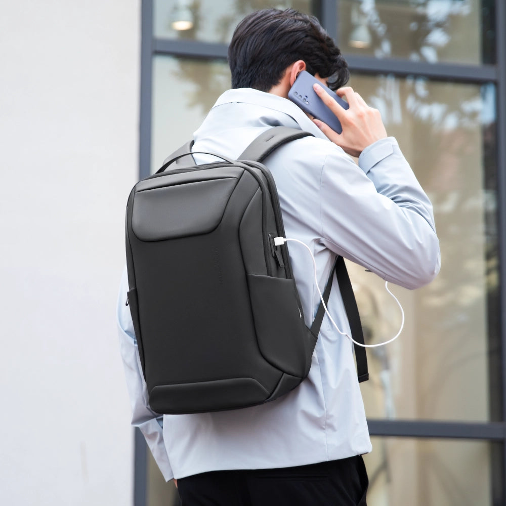 Man in light gray coat wearing MarkRyden Eminence stylish black leather waterproof backpack with USB port