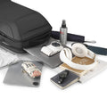 Eminence black leather waterproof backpack with multiple compartments and USB port, surrounded by laptop, camera, headphones, and travel essentials.