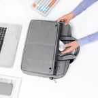 Gray MarkRyden Tech Commuter Computer Briefcase 14/15.6 inch with hands inserting mouse into side pocket, laptop and keyboard nearby.