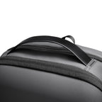 Close-up of gray futuristic minimalist backpack featuring curved black top handle and durable fabric, designed for modern travelers.