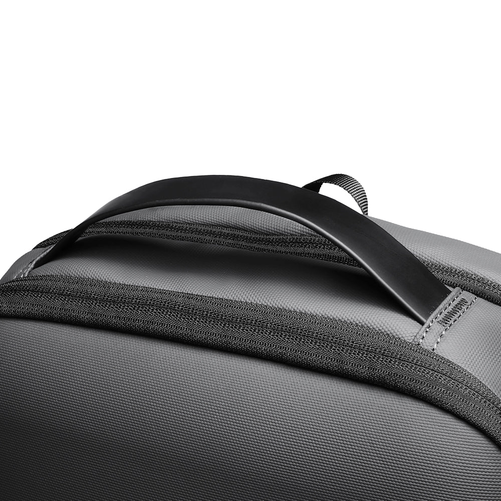 Close-up of gray futuristic minimalist backpack featuring curved black top handle and durable fabric, designed for modern travelers.