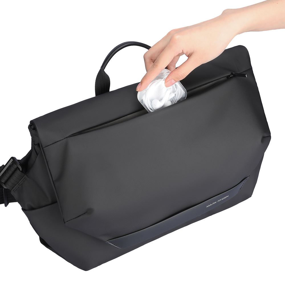 Black MarkRyden PostmanPro All-Rounder Messenger Bag with hand placing earbuds into zippered pocket.