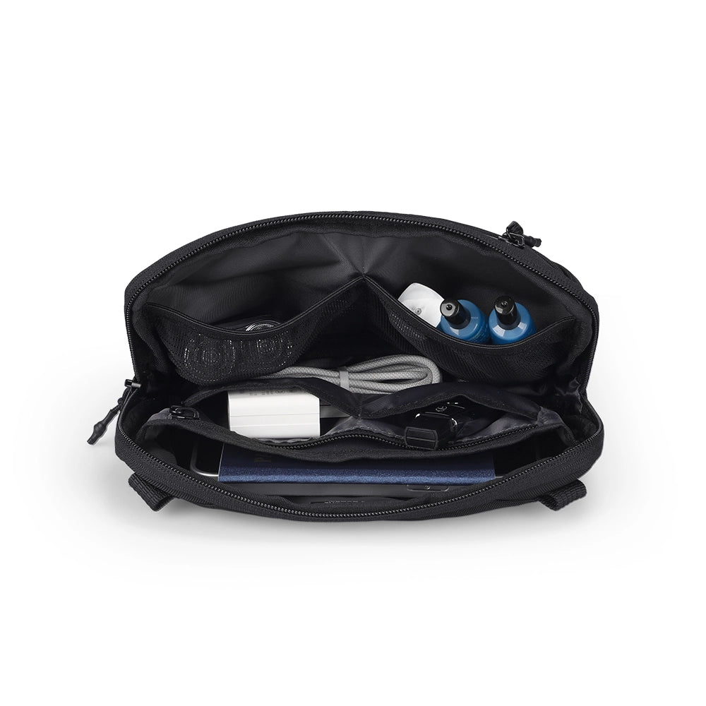 Black Switchstorage IV Convertible Toiletry Crossbody Bag with multiple compartments holding phone, charger, cables, and small bottles for organized travel.