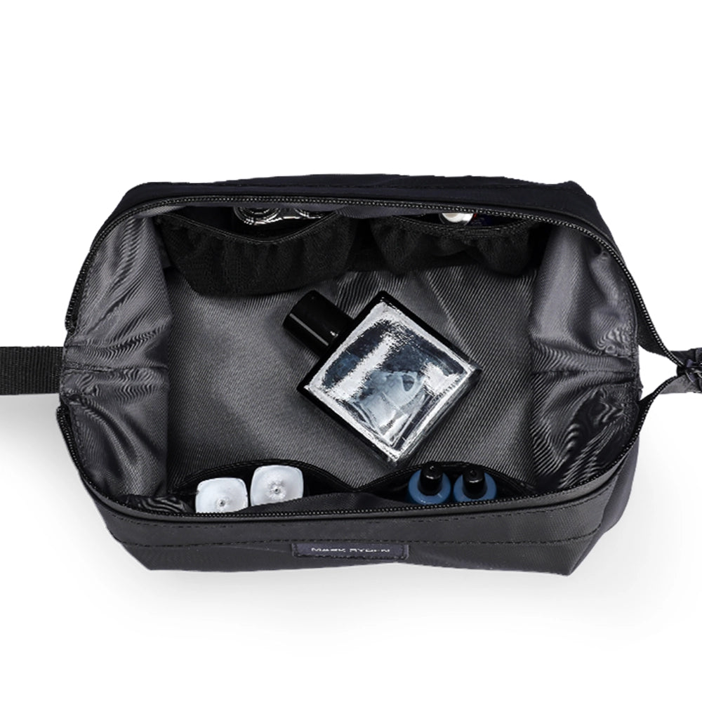 Inside view of black MARKRYDEN Switchstorage V toiletry bag with gray interior, showcasing wet and dry compartments holding perfume and small toiletries for organized travel.