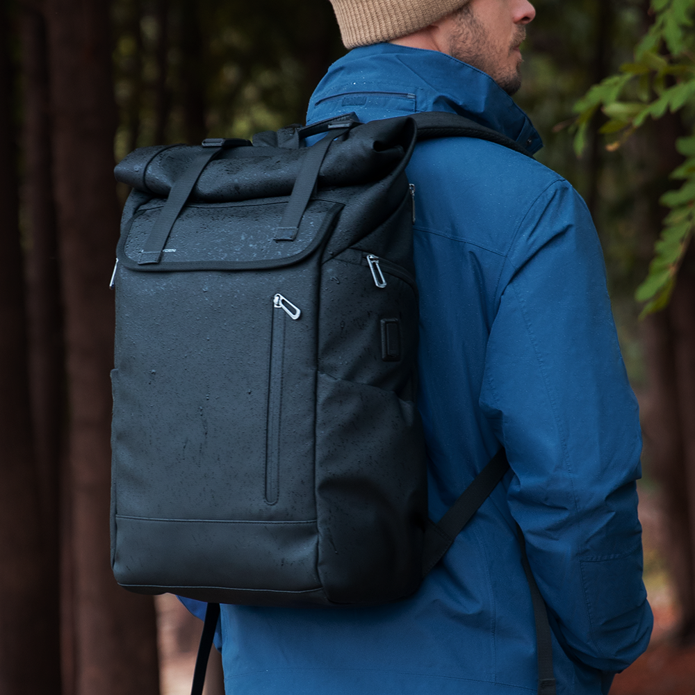 MarkRyden black multifunctional travel backpack with roll-top, worn outdoors