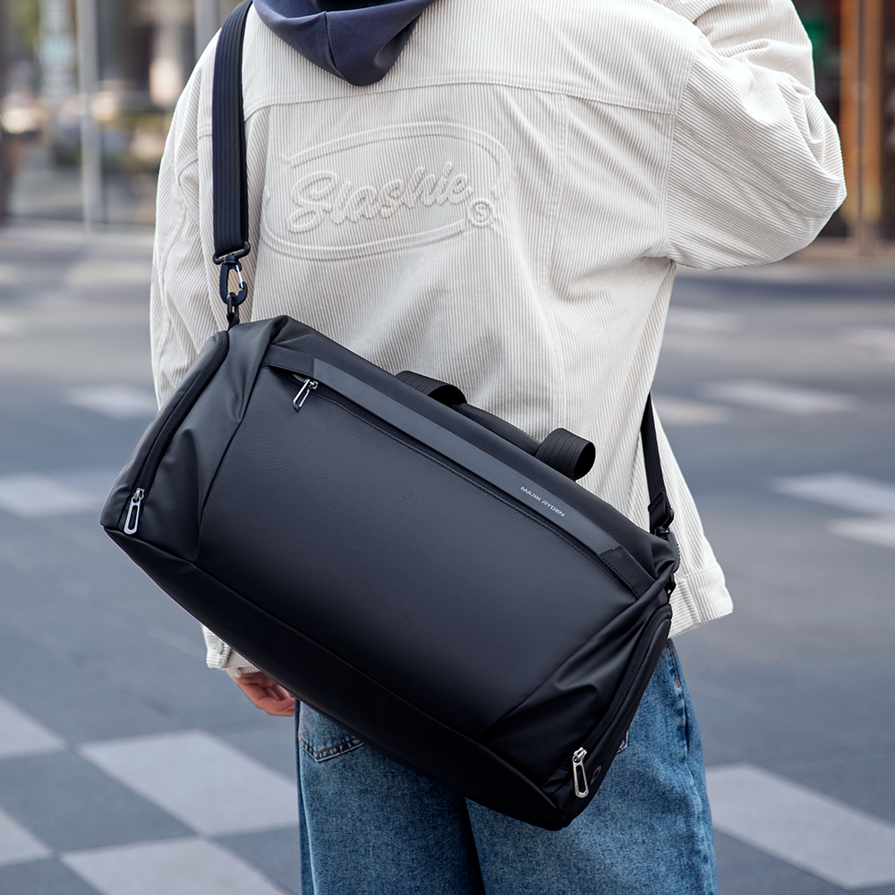 Black leather fitness sports handheld crossbody multifunctional bag by MARKRYDEN, featuring zippers and adjustable strap, carried over shoulder.