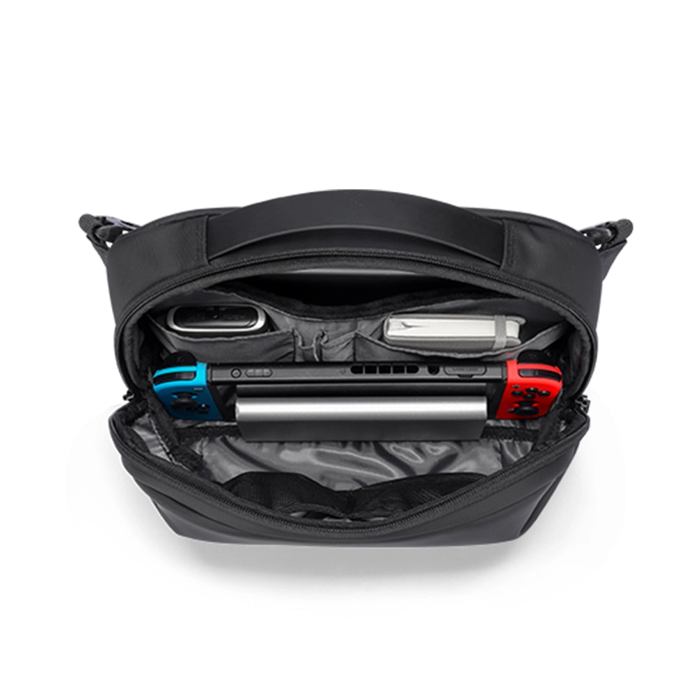 Open black waterproof PU leather sling bag with interior compartments holding a Nintendo Switch and small gadgets, for modern daily use.