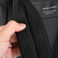 Hand holding black mesh fabric of Mark Ryden DynaPack laptop bag with brand label