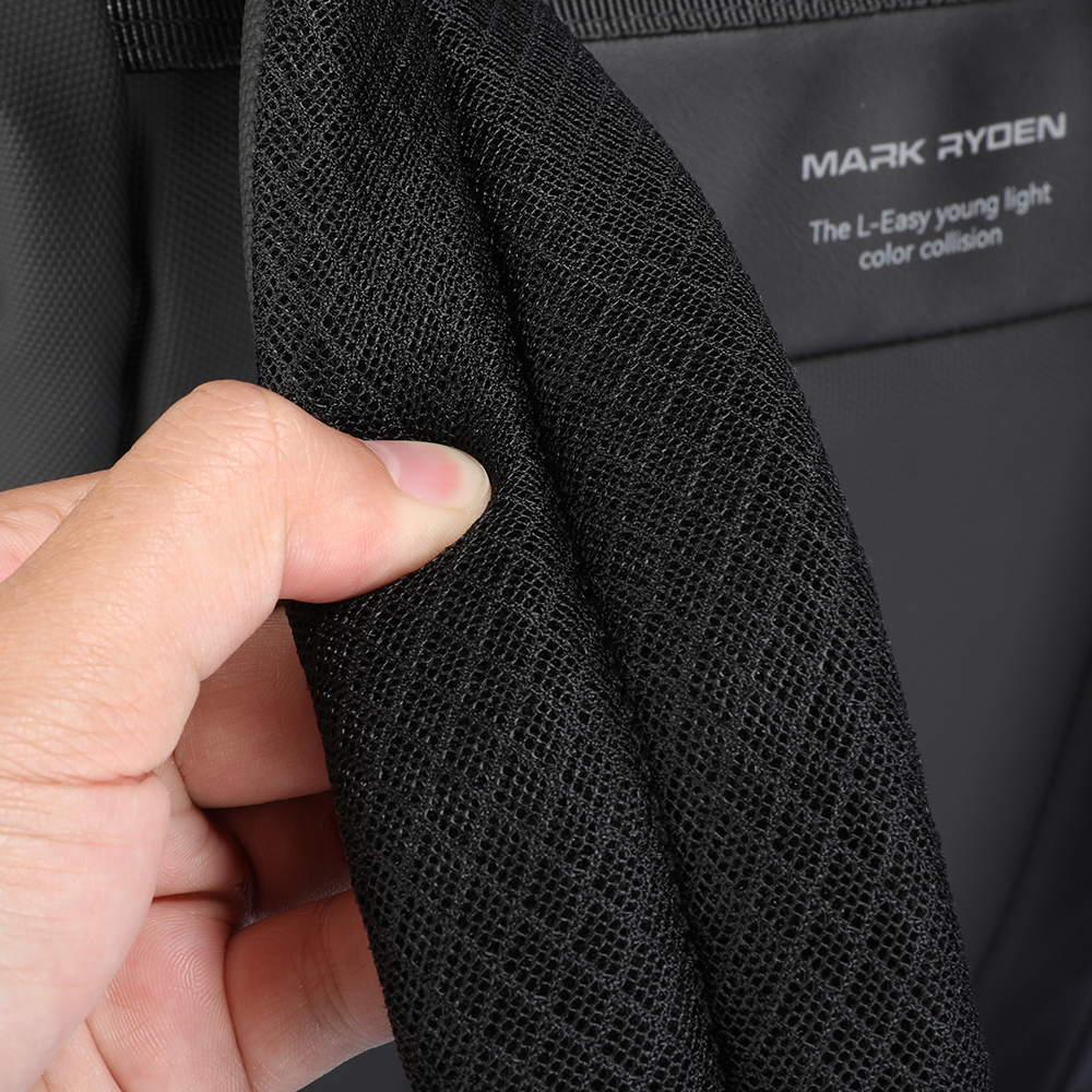 Hand holding black mesh fabric of Mark Ryden DynaPack laptop bag with brand label