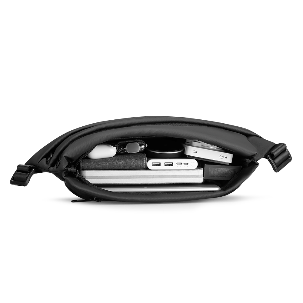 Black leather Voyager messenger bag with open interior holding laptop, power bank, USB hub, and accessories, highlighting spacious storage capacity for modern travelers.