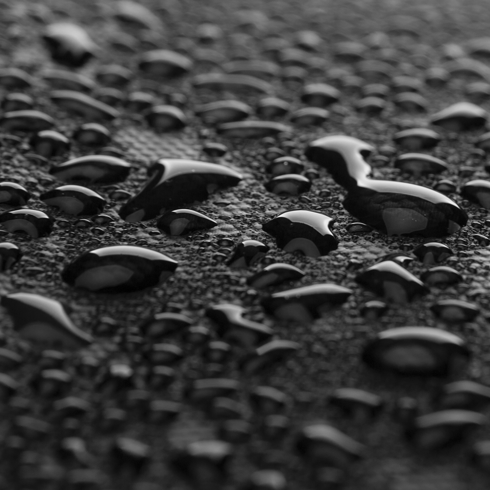 Water droplets on black backpack material showcasing waterproof feature - MARKRYDEN travel essentials