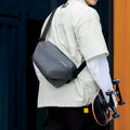 Fingon Ⅰ gray leather large capacity city commuter daily messenger bag worn over shoulder, paired with skateboard for urban commuting.