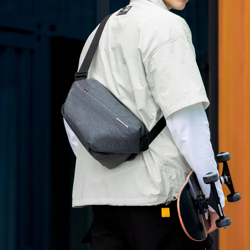 Fingon Ⅰ gray leather large capacity city commuter daily messenger bag worn over shoulder, paired with skateboard for urban commuting.