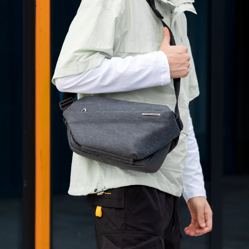 Gray Fingon anti - theft large capacity messenger bag worn by man in city - MARKRYDEN commuter bag