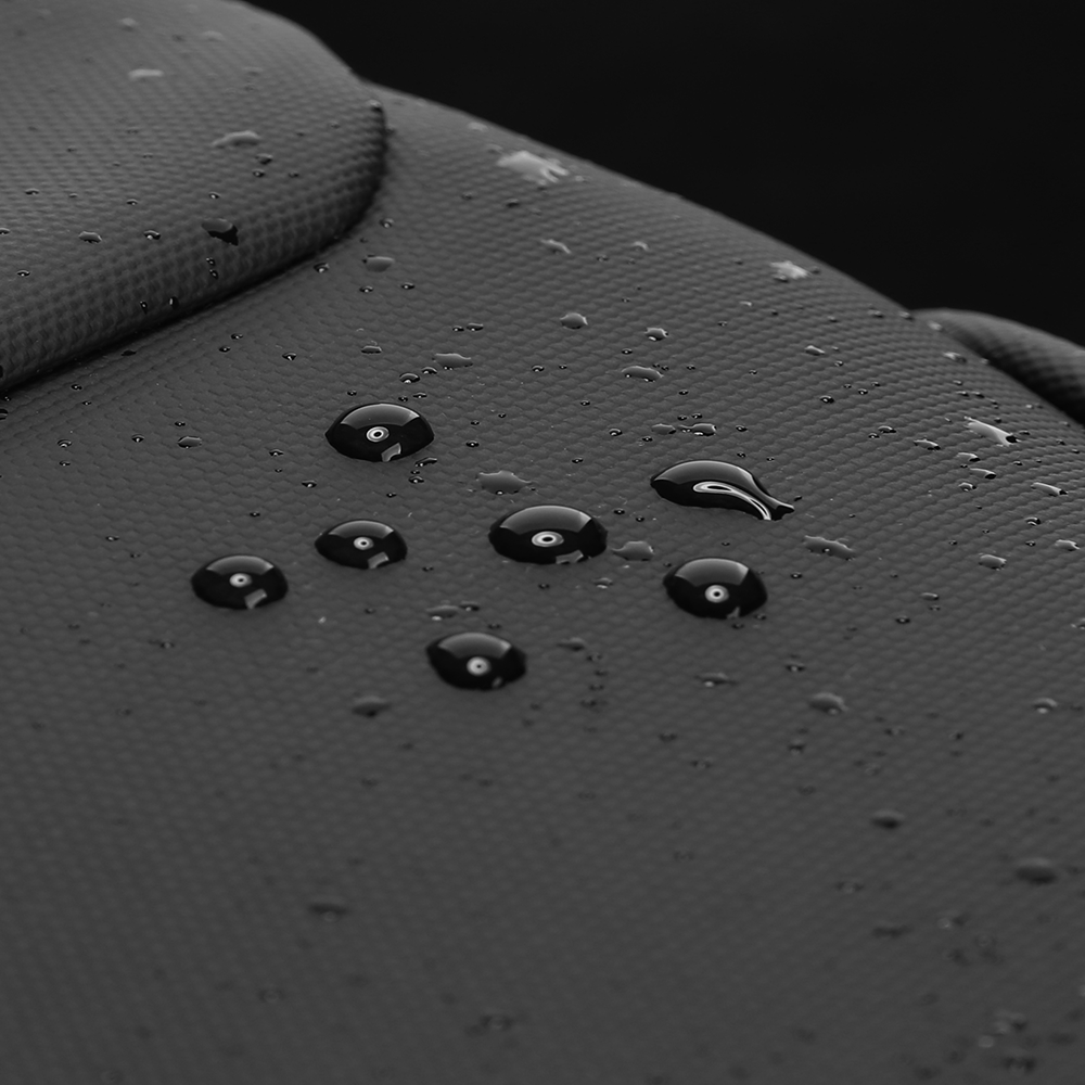 Close-up of water droplets beading on the dark gray leather surface of the Eminence waterproof backpack, showcasing its water-resistant material.