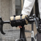 MarkRyden beige cylinder crossbody bag with strap attached to bicycle handlebar - fashion-forward anti-theft accessory